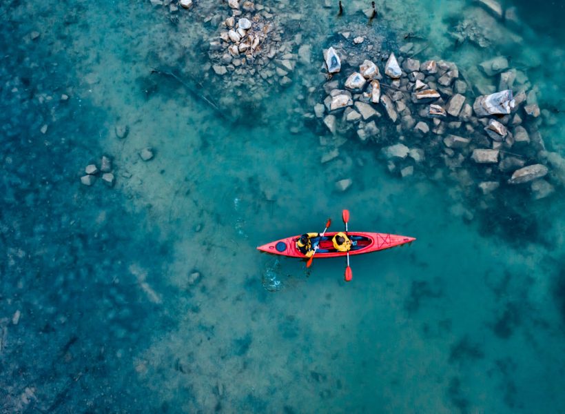 two-athletic-man-floats-red-boat-river